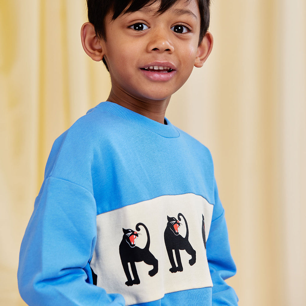Aqua blue cotton sweatshirt with white panel and Mini Rodini iconic panther print. Relaxed fit for kids to 11 years