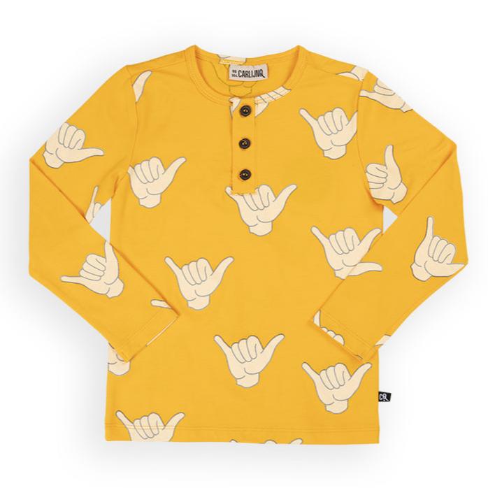 Yellow Henley Organic Cotton shirt with Shaka 'Hang Loose' hands all over. Long Sleeve, 3 button opening at neck, open at wrist and waist.