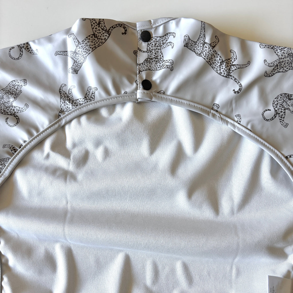 Baby bib with black cheetah print on a light gray background | waterproof | long sleeves | snaps at back of neck | pocket for catching crumbs | back of bib