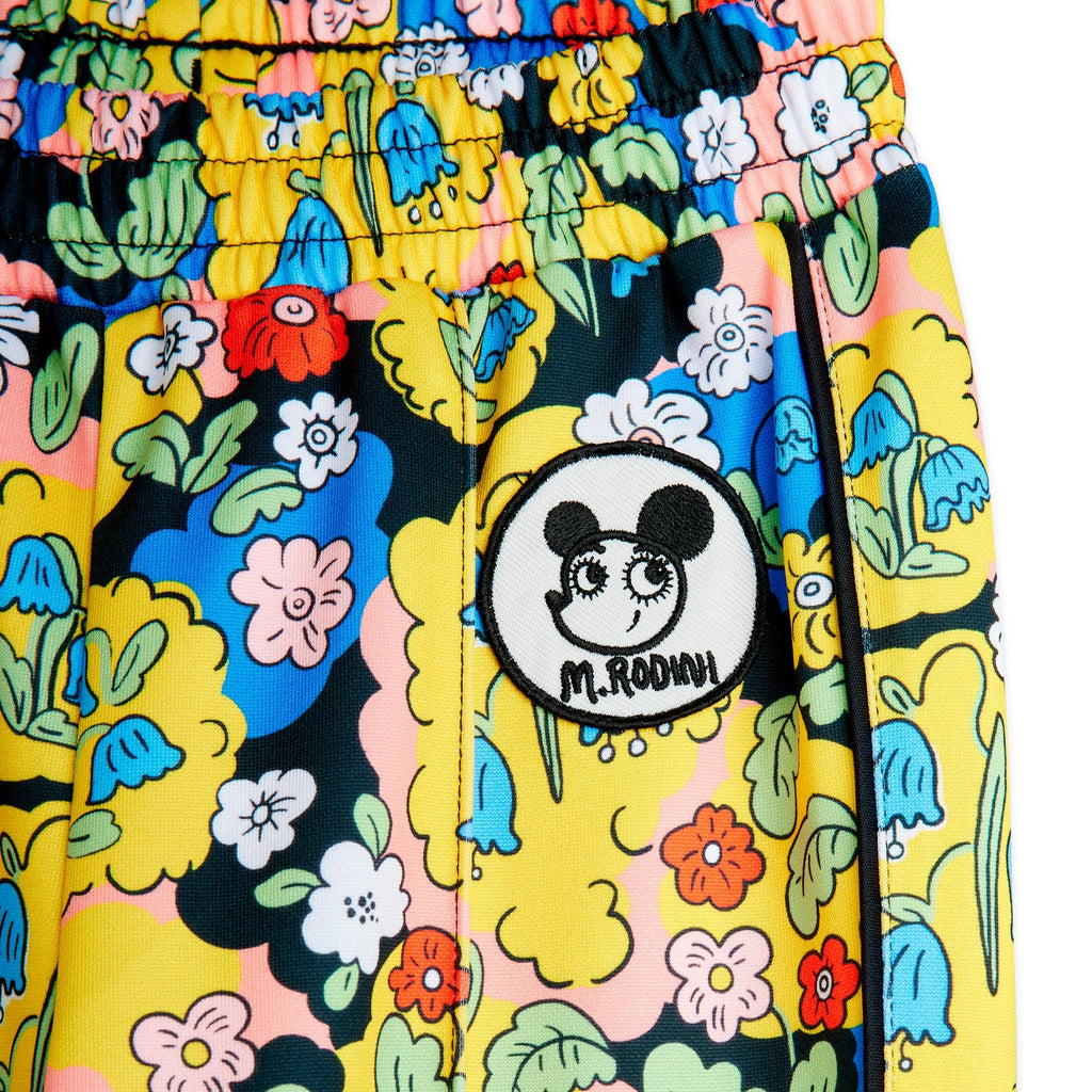 Colorful floral-patterned track pant in soft polyester. Elastic waist, open at ankle, pockets and a cute patch at the hip. Top quality Mini Rodini brand | close up