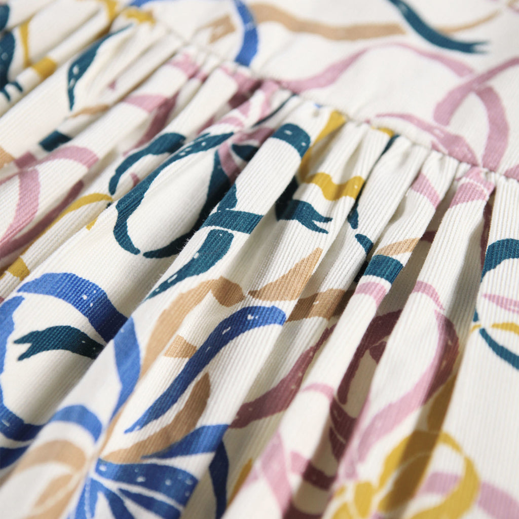 Organic Cotton velvet dress with ribbon print | off-white with blue, pink, gold ribbons | elastic at wrists | button clost in back | full skirt | empire waistline | waist closeup